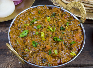 Indian Cuisine Sev Tamatar Also Called Sev Tamaeta or Sev Tameta is Served With Chapati, Papad, Onion or Raita. It is Made With Tomato And Onion Gravy With a Twist of Spicy Sev on Wooden Table