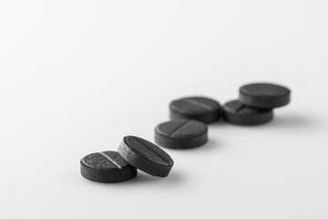 several black medical activated charcoal pills on white background. Isolated