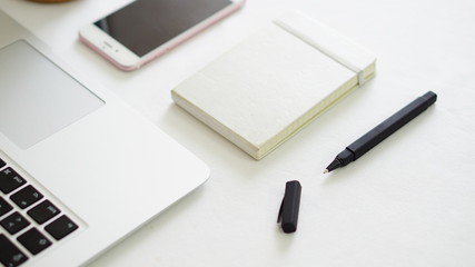 computer phone and notepad with white background table