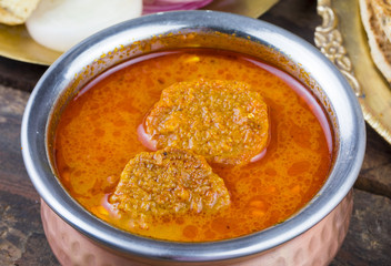Indian Traditional Cuisine Gatta Curry Also Called Gatte ki Sabji or Besan Gatta is a Rajasthan Famous Food Served with Chapati, Onion, Raita or Papad on Wooden Background