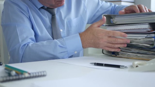 Businessman in Office Room Pointing with Finger Counting Documents and Files