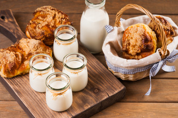 Bread buns, jars with milk on a cutting board 
