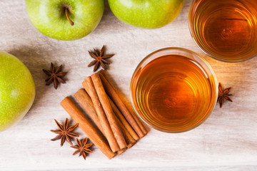 Apple juice in glasses, spices and apples on wooden cutting table 