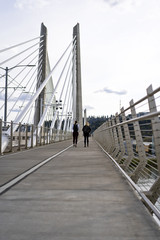 Two girls with backpacks walking through Tilikum Crossing Bridge across the Willamette River in Portland Oregon