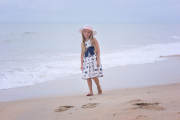 Adorable child  walking beach shore splashing water in blue sea