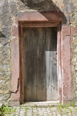 Old wooden medieval door in a stone wall on a sunny day