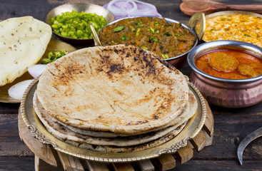 Indian Cuisine Chapati Also Called Roti, Flatbread, Chapathi or Chapatti Served With Sev Tamatar, Gatta Curry, Raita, Papad or Onion on Wooden Background