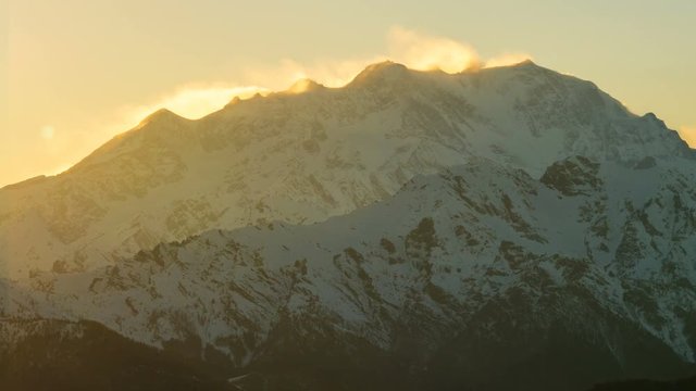 Italian Alps: Monte Rosa mountain range seen from the Valsesia valley, Piedmont, at sunset. The strong wind lifts the snow on the highest ridges. 4K time lapse.