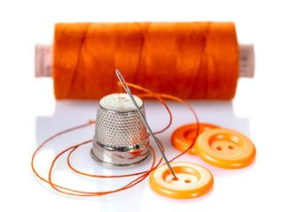 Needle with orange thread and buttons