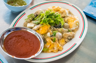 Fried oysters with eeg thai food with spicy sauce on dish.