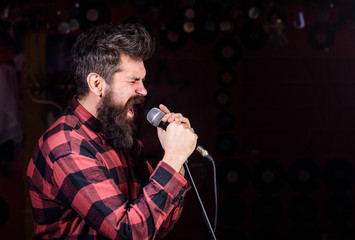 Man with tense face holds microphone, singing song, black background, copy space. Musician with...