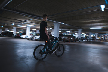 Riding a bike without hands on underground parking. An extreme man rides a bike on the parking lot