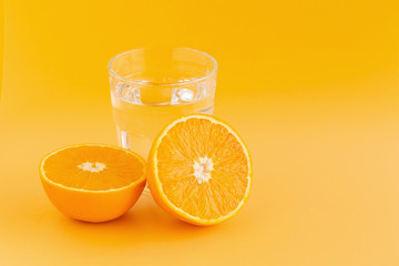 Detox Water with orange in a glass on an orange background