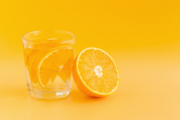 Detox Water with orange in a glass on an orange background