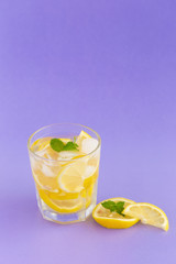 Detox Water with lemon in a glass on a purple background