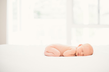 newborn baby sleeping on white bed