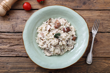 risotto con funghi tradizionale italiano su sfondo tavolo di cucina rustico