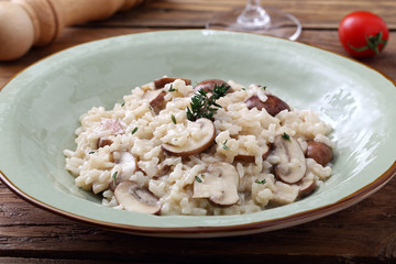 risotto con funghi tradizionale italiano su sfondo tavolo di cucina rustico