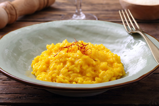risotto allo zafferano tradizionale italiano su sfondo tavolo di cucina rustico