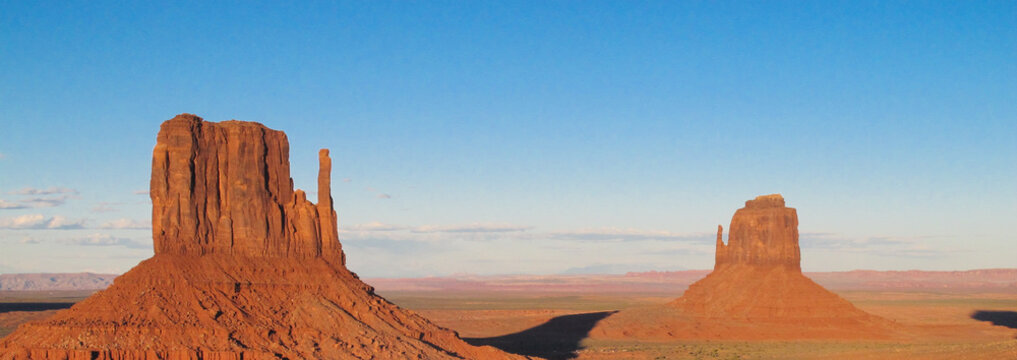Wide view of Monument Valley showing sandstone buttes against a blue sky © Helen