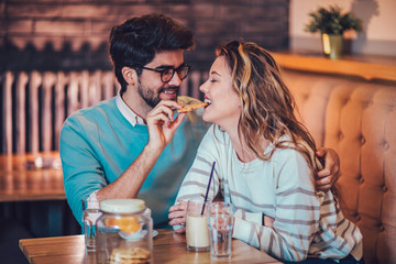  Beautiful loving couple sitting in a cafe sharing cookie. Love and romance concept.