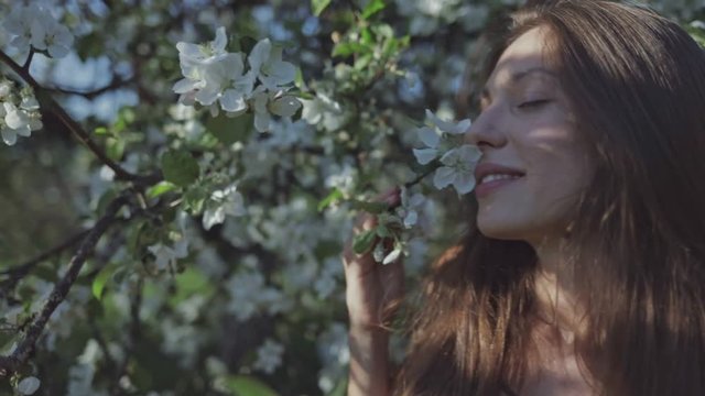 Beauty young woman enjoying nature in spring apple orchard, Happy Beautiful girl in Garden with blooming trees. Slow motion video shooting by handheld gimbal