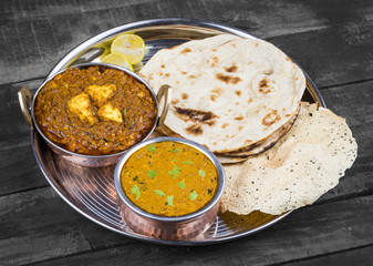 Indian Traditional Thali Food Dal Makhani Served with Chapati, Papad, Kadai Paneer or Lemon Also Know as Dal Makhni or Daal Makhani is a Popular Dish From Punjab. on Vintage Wooden Background