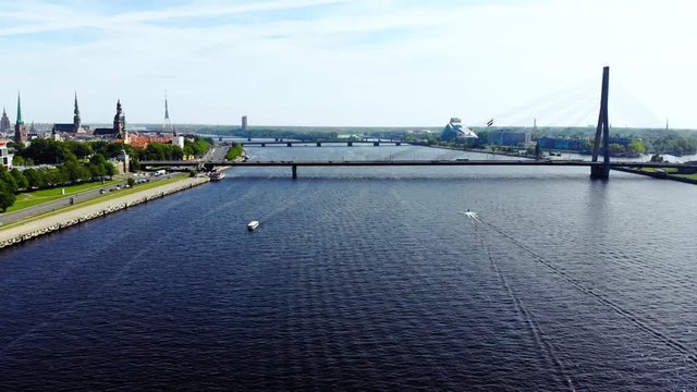 Speedboat, yacht cruising through the river in Riga, Latvia, aerial view of speedboat moving, city landscape on a sunny day