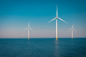 Offshore and Onshore Windmill farm in the ocean ,windmills isolated at sea on a beautiful bright day Netherlands Flevoland Noordoostpolder 