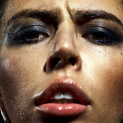large portrait of the girl's face. Eyes, lips, makeup, crazy emotion. Water runs down the skin. The chain in his teeth.