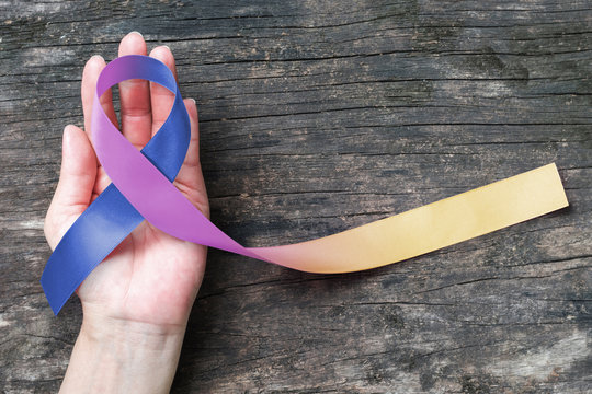 Bladder cancer awareness marigold blue purple  ribbon on helping hand suport (isolated with clipping path) .