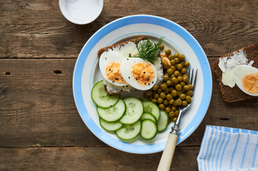 Sandwich with egg, green peas and cucumber on a plate