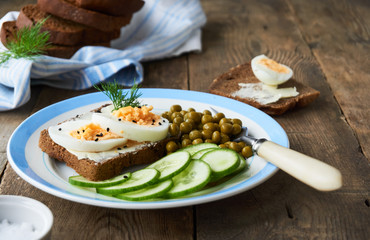 Sandwich with egg, green peas and cucumber on a plate