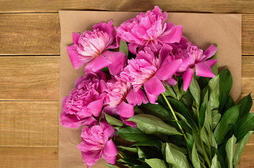 A bouquet of pink peonies on wrapping paper on a wooden table. festive mood. celebration. space for text
