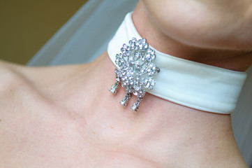 Necklace on the woman's neck. A beautiful silver brooch on a white ribbon.