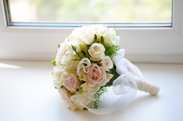 Beautiful wedding bouquet of white and pink roses by the window.
