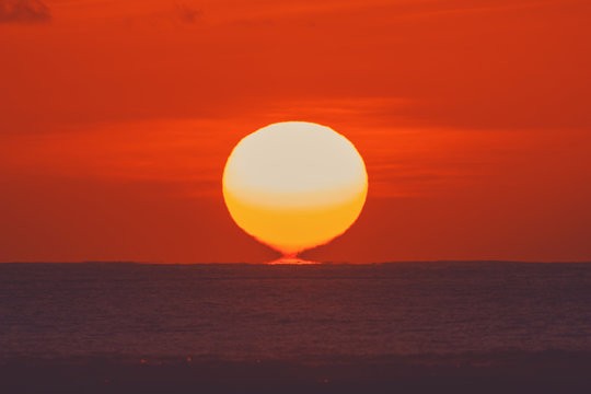 Fototapeta Sunrise over ocean horizon photographed with big telephoto lens.