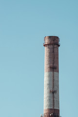 High red and white striped tube on background clear blue sky close-up. Thermal power plant with copy space.