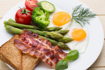 Fried eggs with bacon on the wooden table.