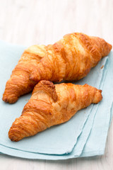 Tasty buttery croissants on old wooden table.