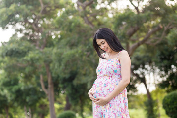 Fototapeta premium Beautiful pregnant woman relaxing outside in the park