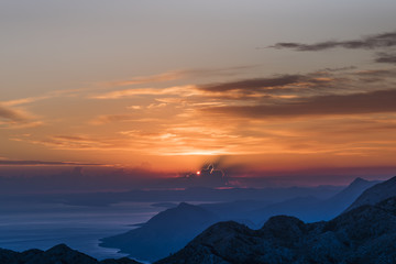  Sunset panorama in Biokovo Nature Park with interesting luminous clouds, the Dalmatian coast of the Adriatic Sea and mountain ranges in shades of blue - View from Sveti Jure, Croatia