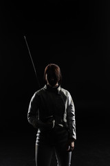 female fencer standing with sword on black background