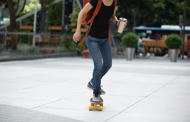 woman skateboarding with coffee cup in hand on city street