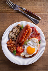 Full English or Irish breakfast on wooden table. Nutritious and healthy morning meal. Overhead, vertical