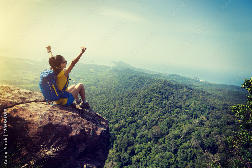 Wall mural successful woman hiker cheering on mountain peak cliff edge