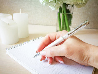 Женщина пишет в блокноте красивой ручкой.