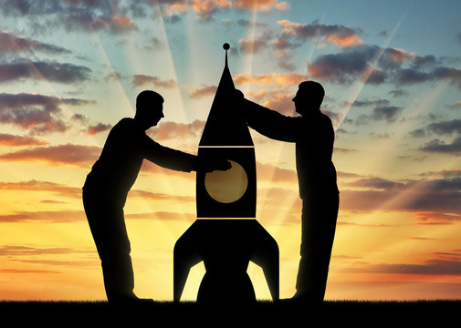 Silhouettes of two men picking up a rocket