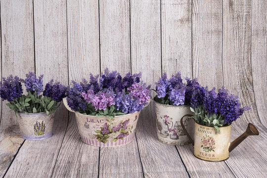 Flores de lavanda en maceteros decorados y regadera decorada.