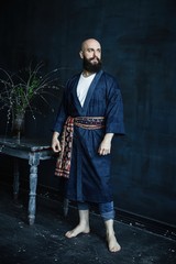 Handsome young bearded man posing against grunge wall background